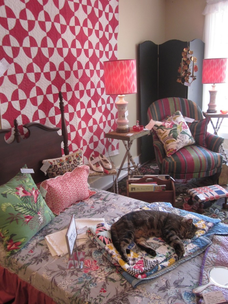 Red quilt $125 Pair of pink lamps $195/pair Green barkcloth cushion $85 Patch quilt $200 Striped armchair $175